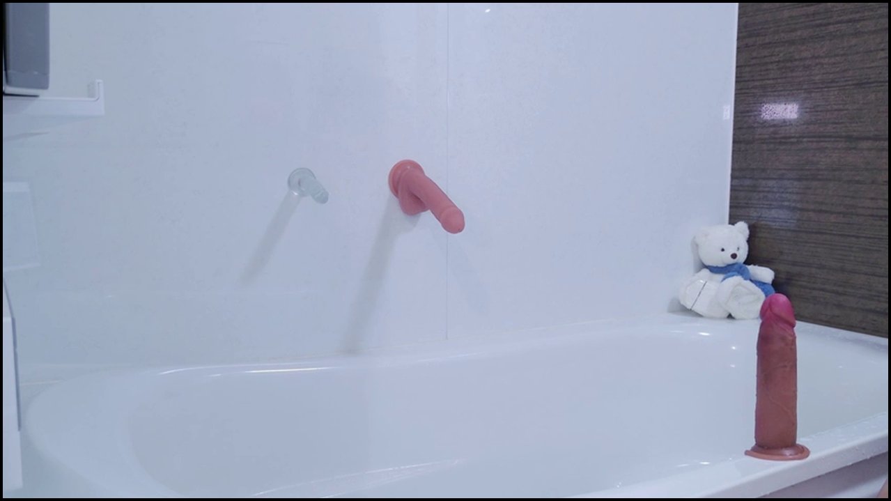 Video of a light-skinned, nude, transgender person with a small penis, lifting a blue crop top to reveal flat chest. Standing in a modern bathroom wit